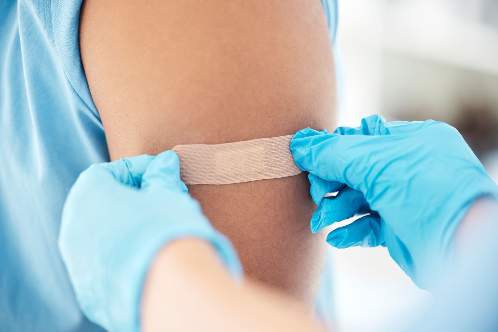 Gloved hands applying a bandage to a person’s upper arm
