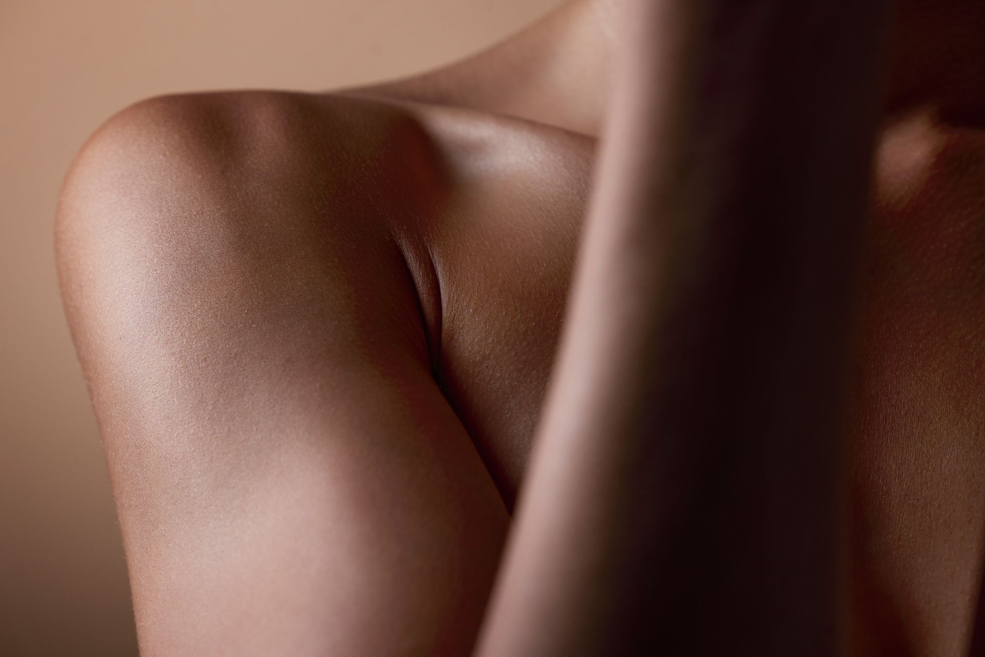 Close-up of a bare shoulder and neck with warm, soft lighting against a dark background Close-up of a bare shoulder and neck with warm, soft lighting against a dark background