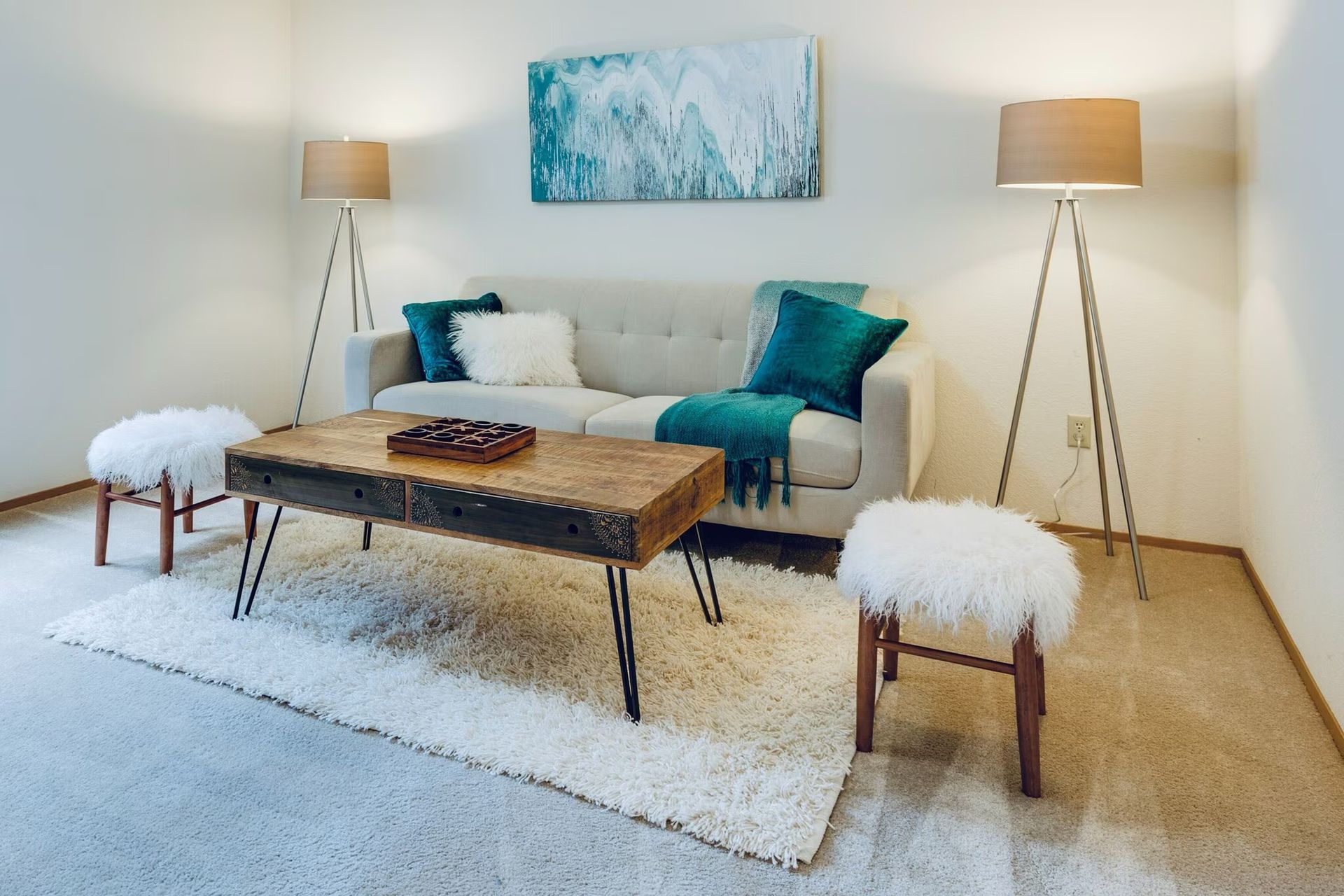 Photo of a living room with a couch, coffee table, some stools and lamps