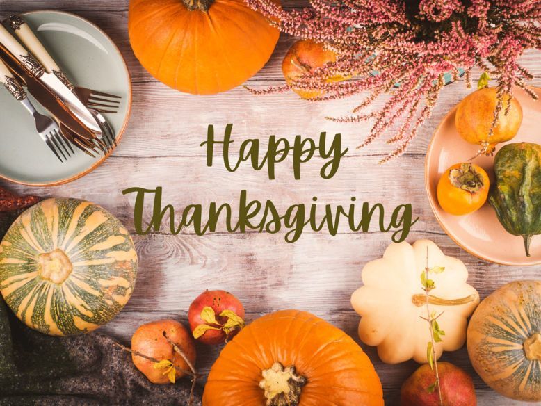 Thanksgiving table setting with pumpkins, squash, plates, and cutlery; festive.
