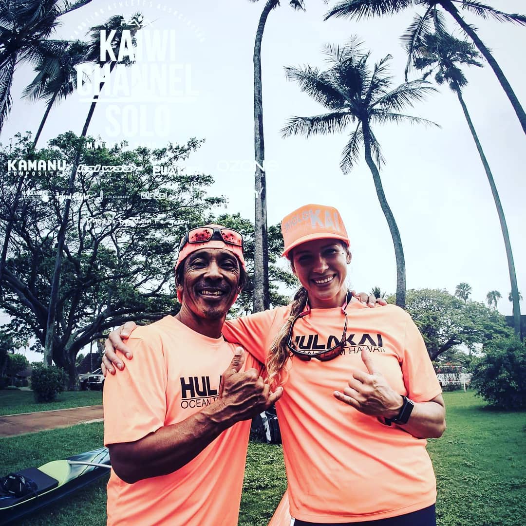 A man and a woman are posing for a picture in front of palm trees