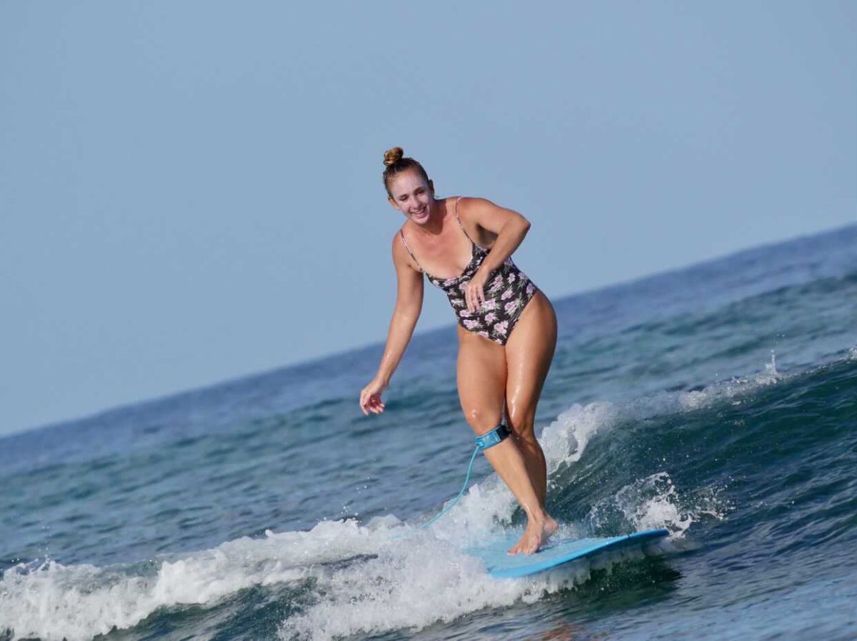Person surfing on a blue wave under a clear sky.