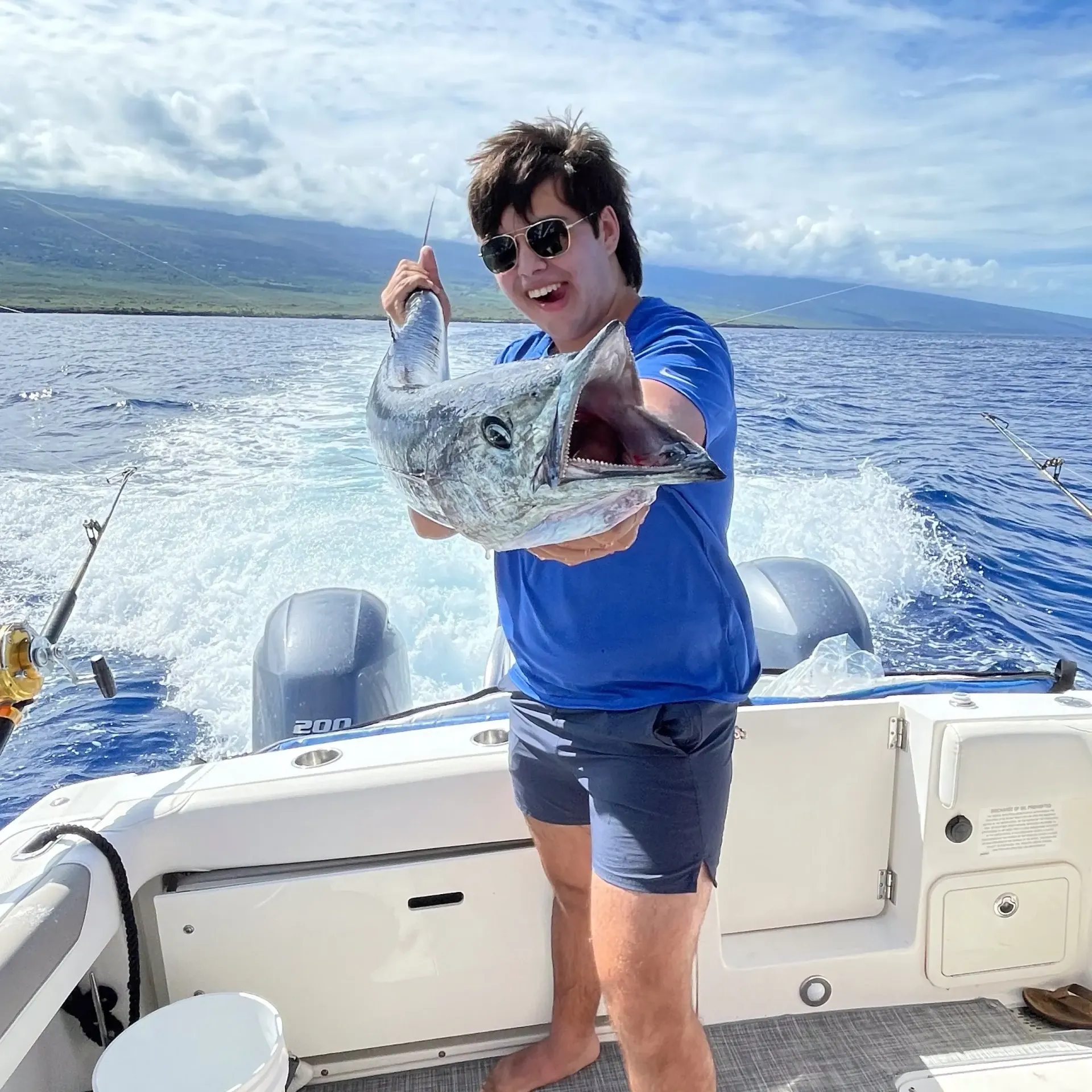 Angler holding a wahoo caught onboard a private Kona deep sea fishing charter