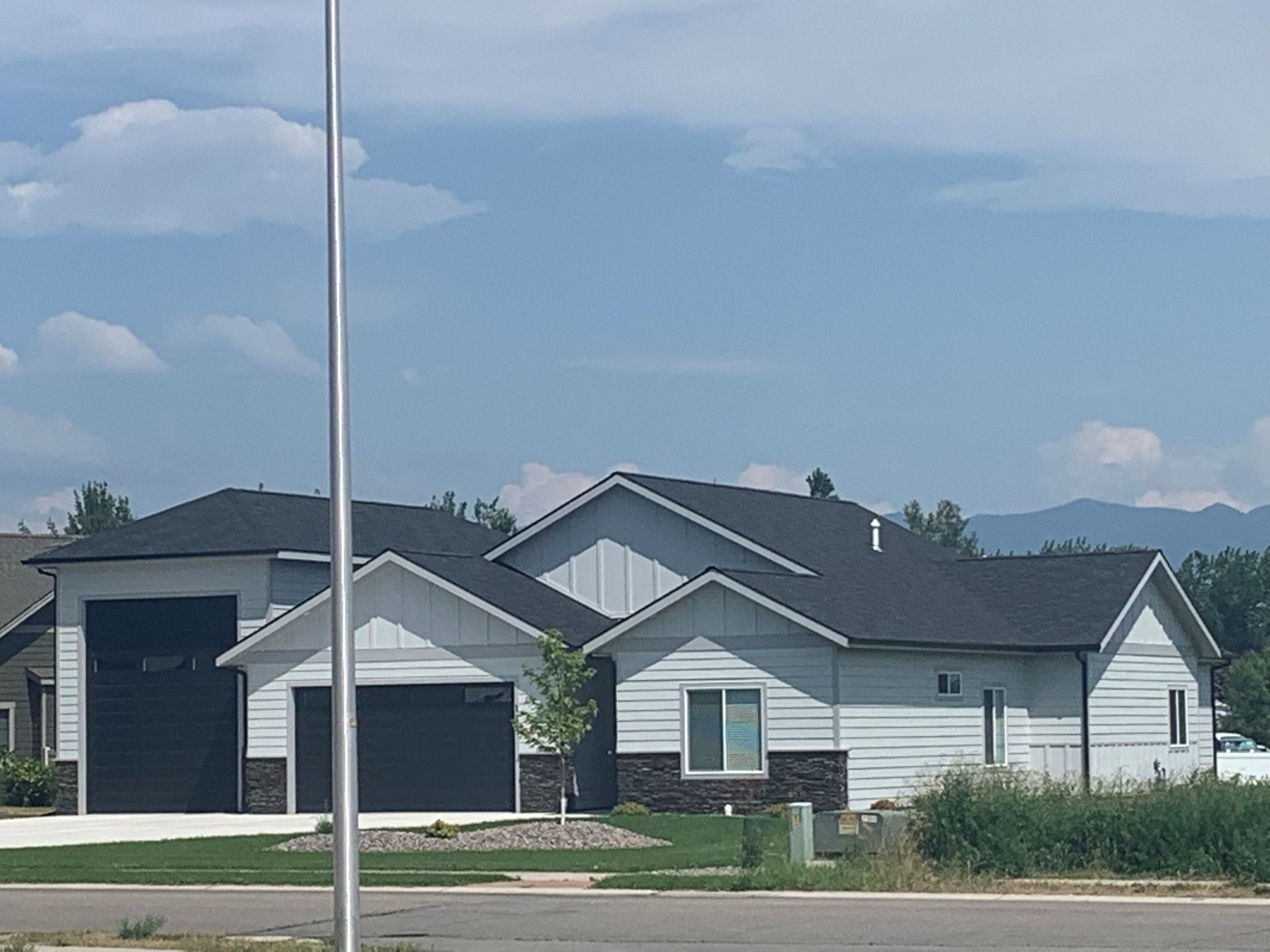 New suburban houses with gray roofs under a blue sky, viewed from across a street