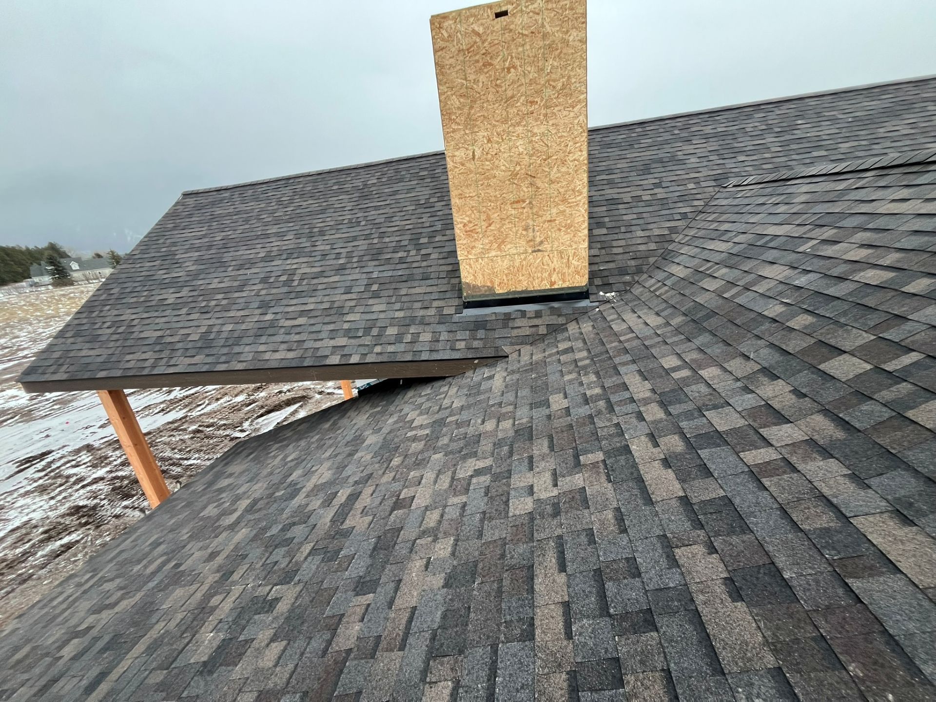 New shingle roof with a plywood chimney vent in daylight
