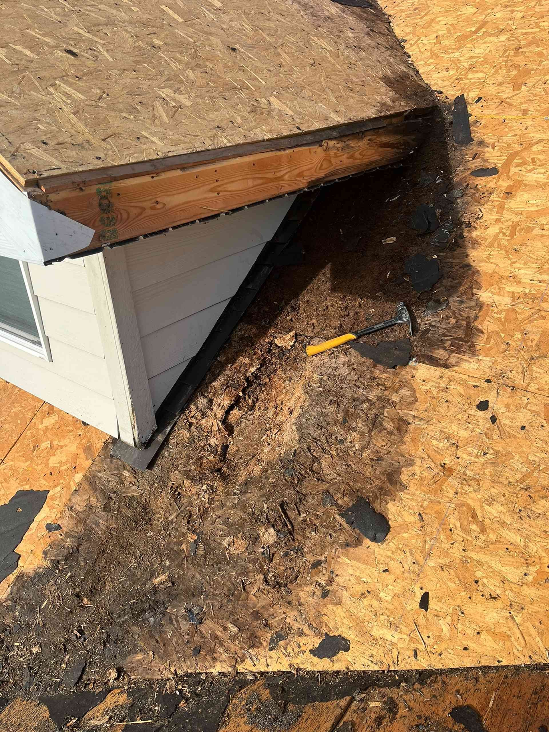 Charred roof edge and siding on a damaged building, with black scorch marks spreading onto the ground.