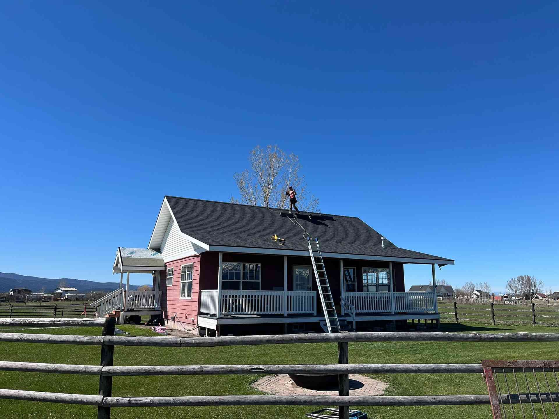 Small house with a porch behind a wooden fence under a clear blue sky