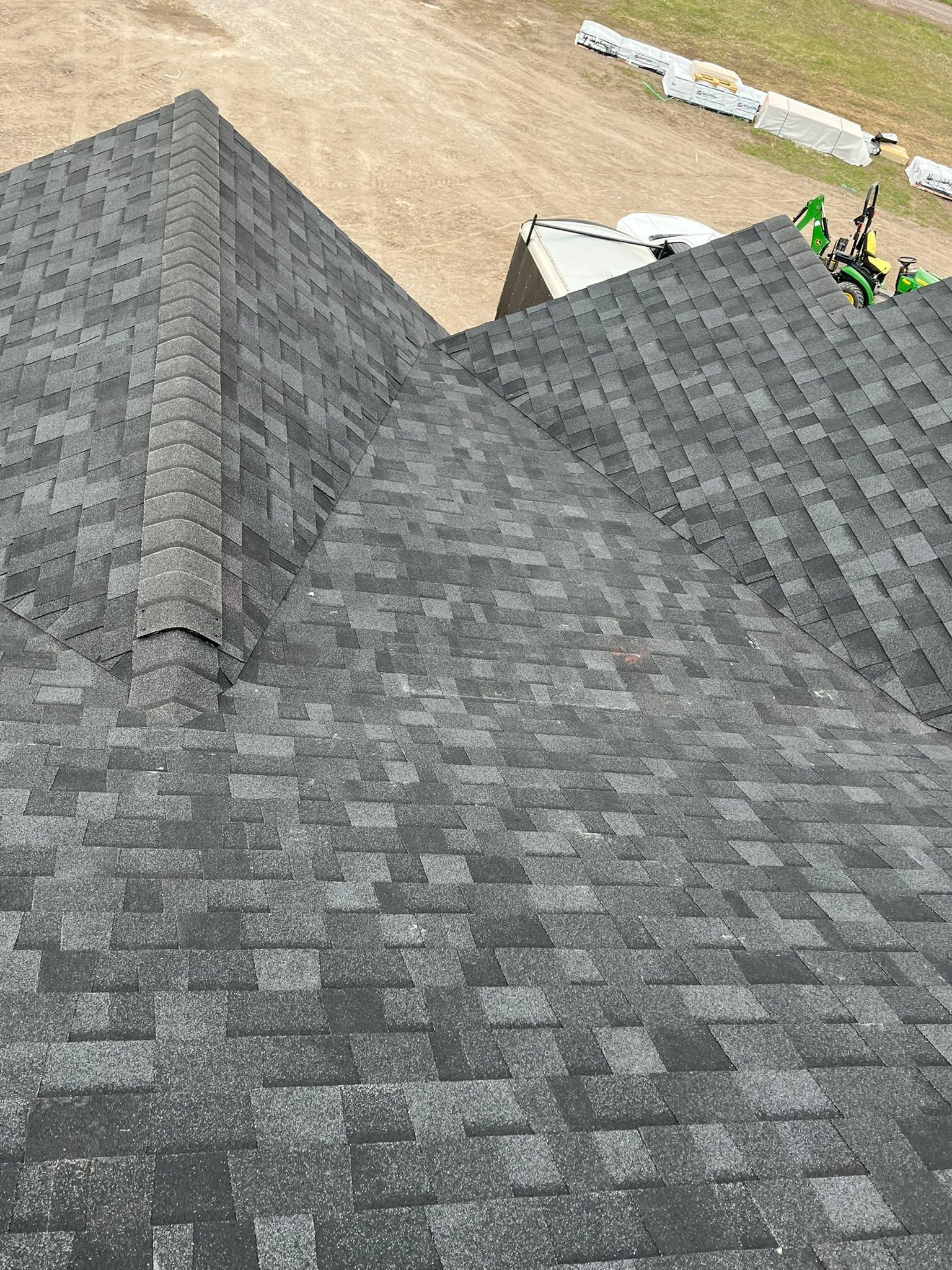 Steep gray shingle roofs below a sandy landscape with a few small figures at the top right