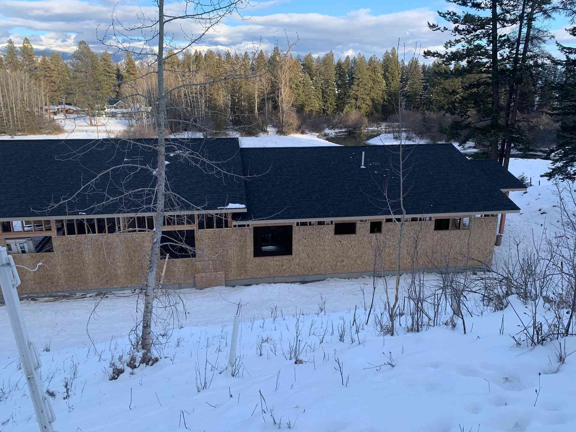 Snow-covered house with a dark roof in a wooded winter landscape
