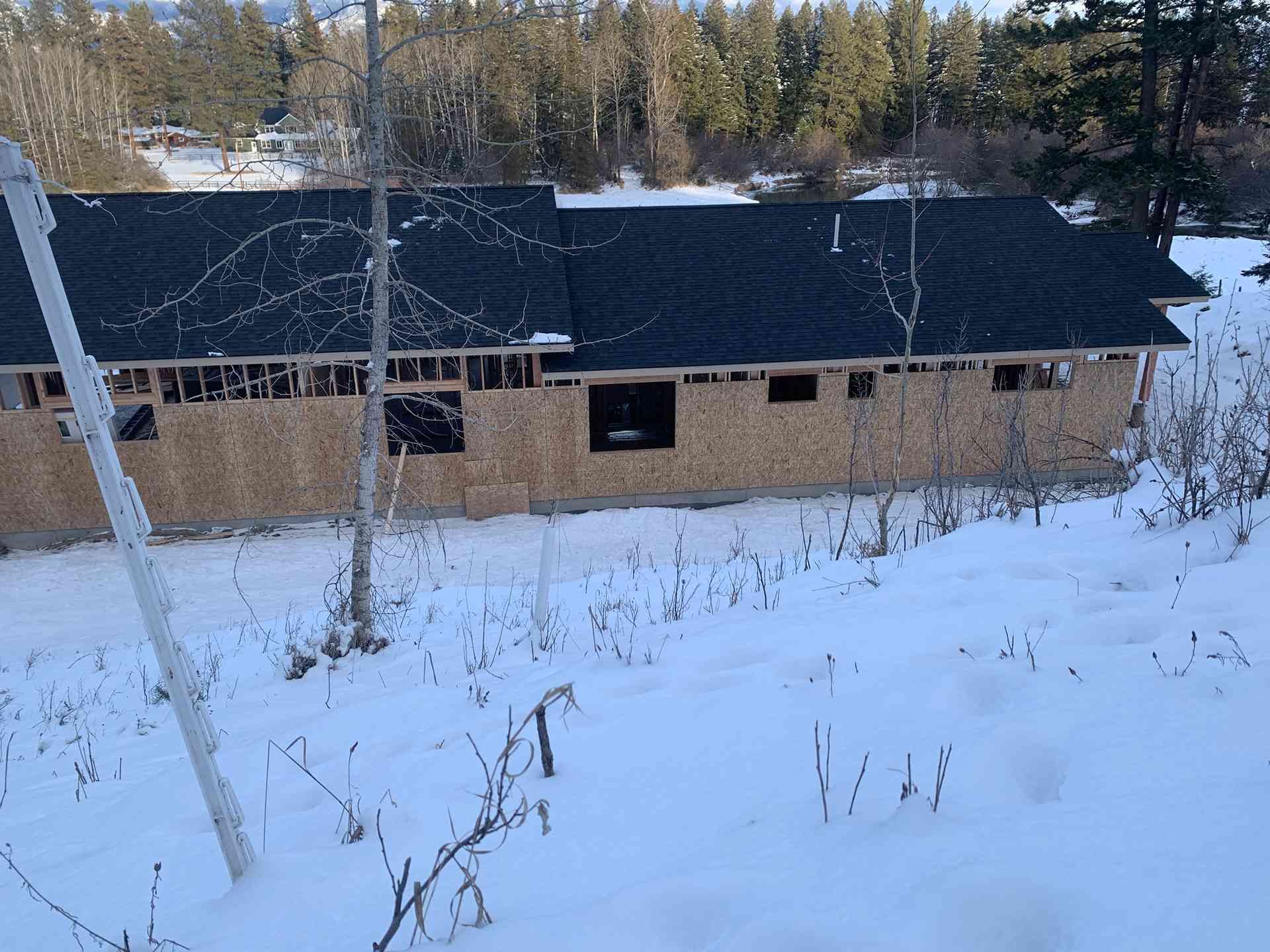 Snow-covered building with a dark roof in a wooded area
