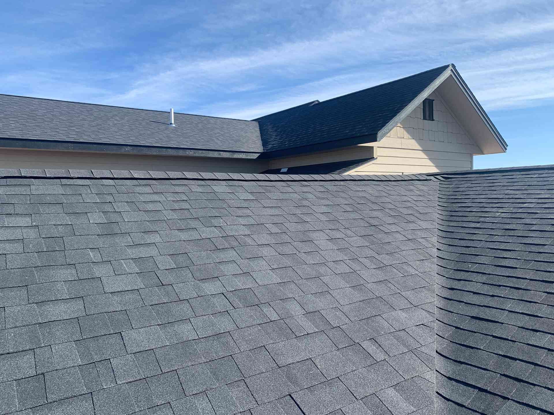 Gray shingle roof with a dormer under a blue sky