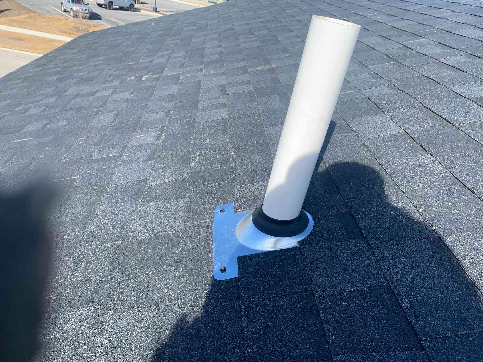 White vent pipe on a shingled roof, mounted near the roof ridge.