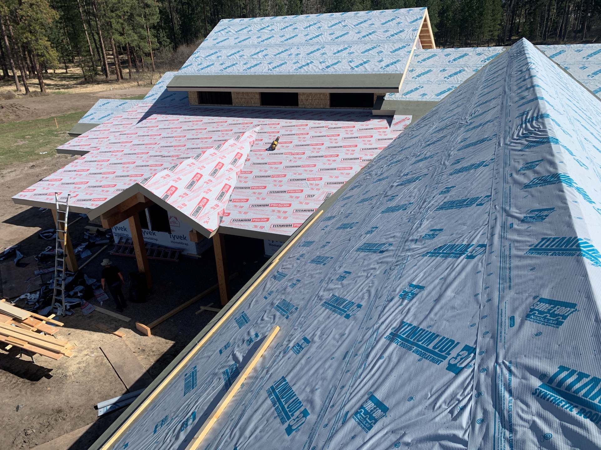 Partially built house with steep rooflines covered in blue and pink roofing underlayment