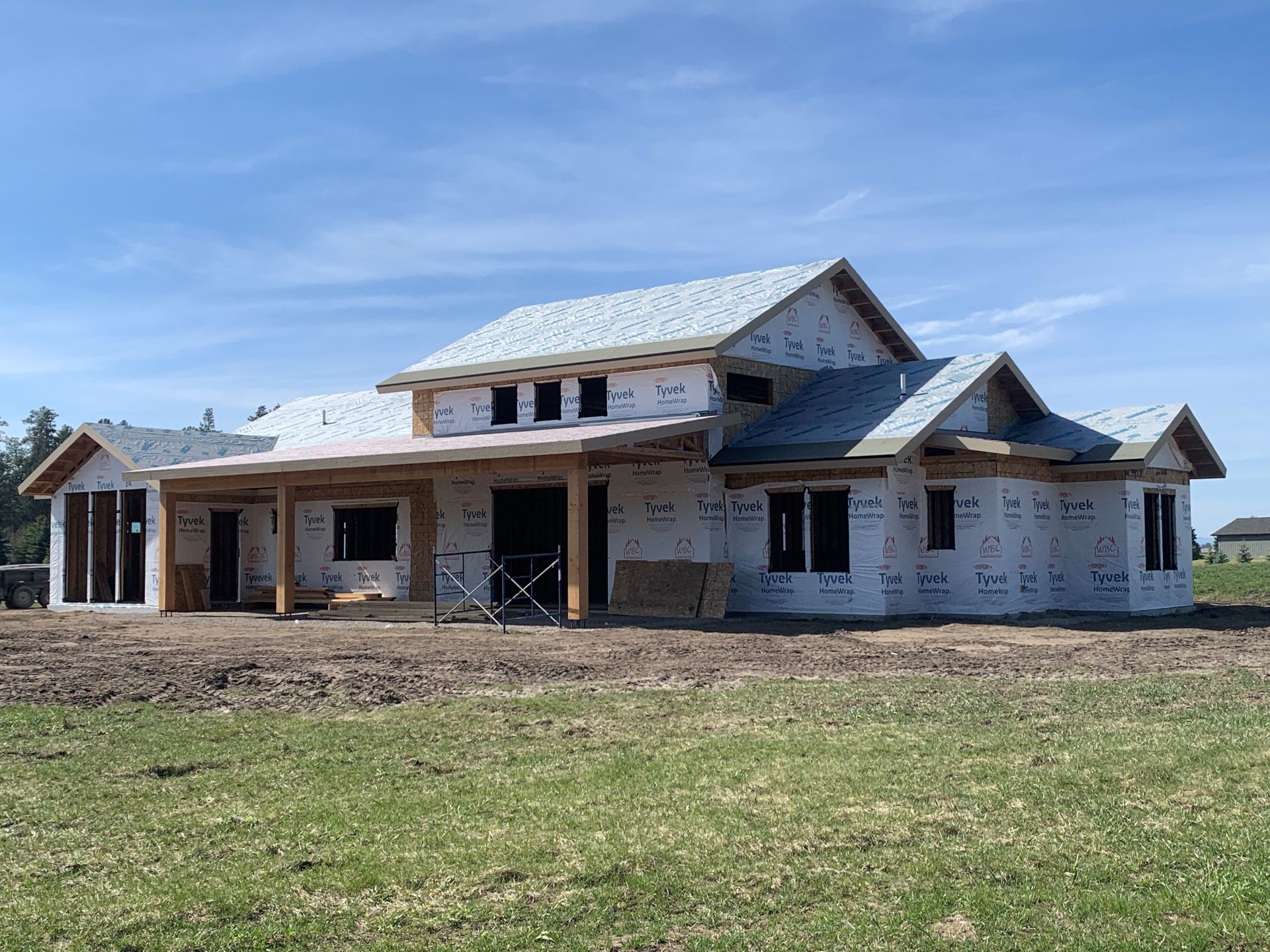 Partially built house with stone facade and white siding under a blue sky