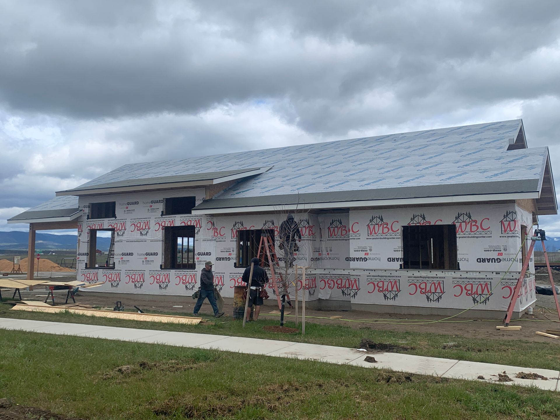 Partially built house with people outside under a cloudy sky