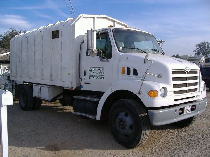 White utility truck parked outdoors on a sunny day, side view with a cargo box and black wheels