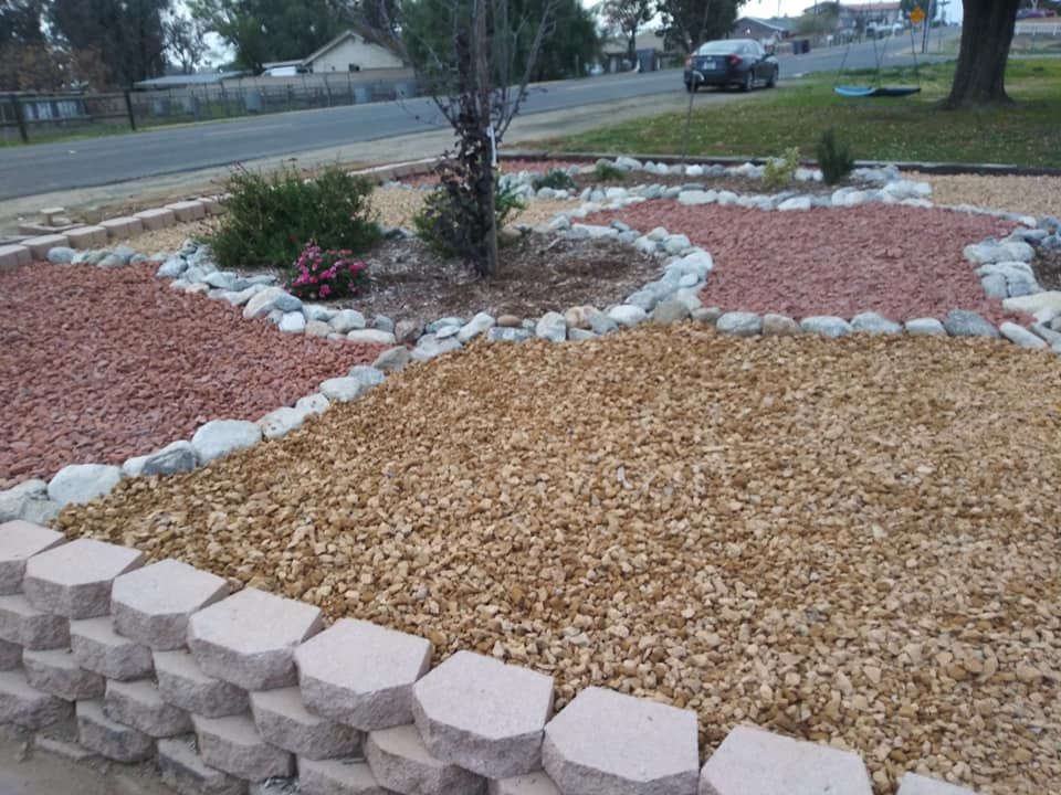 Landscaped yard with tan mulch, rock borders, and stone edging near a street