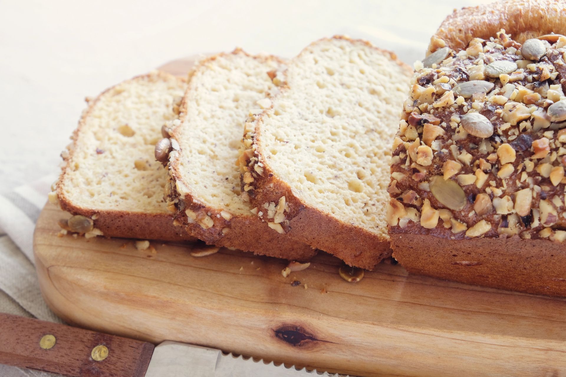 Pan de molde con cobertura de nueces sobre una tabla de madera, con un cuchillo en primer plano.