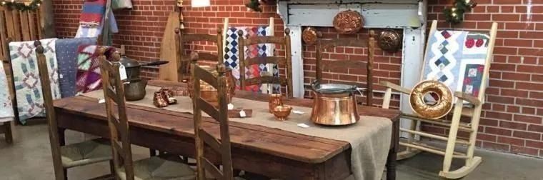Rustic dining setup with wooden bench, table, copper pots, and patterned chairs in a cozy room
