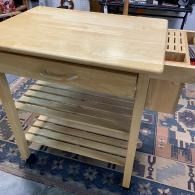 Light wood rolling kitchen cart with slatted lower shelf on a patterned rug