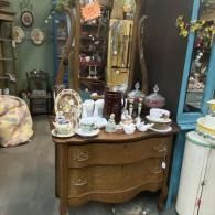 Antique dresser with porcelain tea set and decorative glassware in a vintage shop display