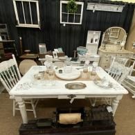 White vintage table with assorted antique dishware and decor in an outdoor patio setting