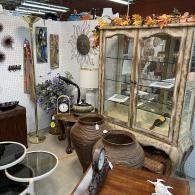 Antique shop display with ceramic pots, glass cabinet, wall decor, and vintage furniture