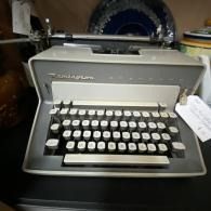 Grey vintage typewriter on a desk with paper loaded in the carriage.