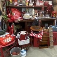 Cluttered antique shop display with shelves of vintage household items, baskets, and wooden furniture