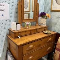 Wooden dresser with mirror and small decor items in a cozy room.