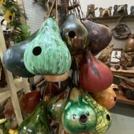 Colorful, teardrop-shaped hanging sculptures with round holes in a workshop or gallery setting