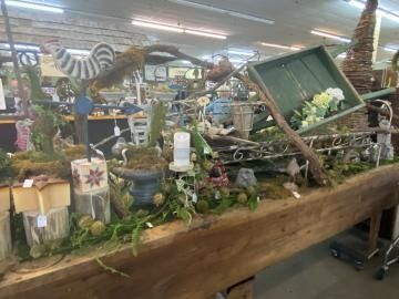 Rustic indoor display with wood planter, greenery, candles, and decorative branches in a store.
