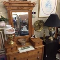 Vintage dresser with mirror, lamps, and decorative objects in a shop display