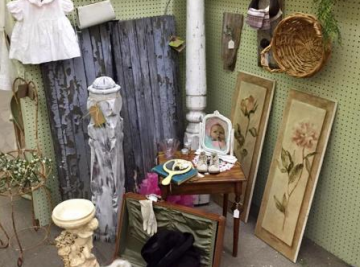 Vintage display of rustic decor with framed botanical prints, woven baskets, and a weathered door