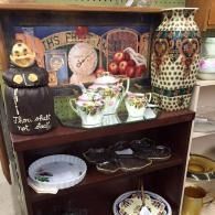 Decorative display shelf with Halloween-themed pottery, candles, and small dishes in a shop.