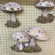 Decorative mushroom figurines with spotted caps and grass-like bases on a pegboard display