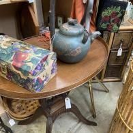 Round wooden table with blue teapot, floral box, and rustic decor in a shop display