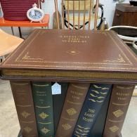Leather-bound books stacked as a square coffee table in a room with chairs behind it