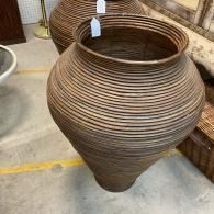 Large brown ribbed ceramic vase with a narrow base, displayed indoors on a concrete floor.