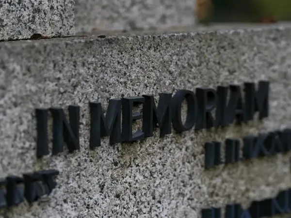 Close-up of a memorial plaque with dark raised letters on gray stone