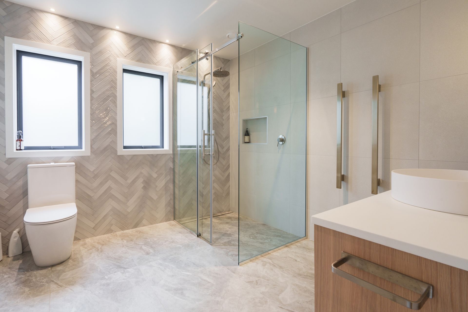 A custom glass shower door stall and toilet are featured in a modern bathroom with a sleek design.