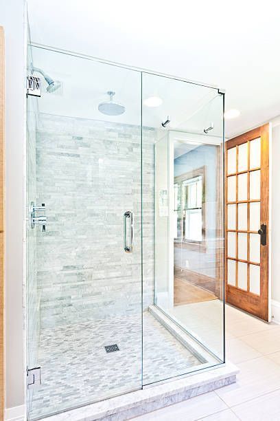 Spacious walk-in shower featuring custom shower glass doors, built-in shelf, and towel rack