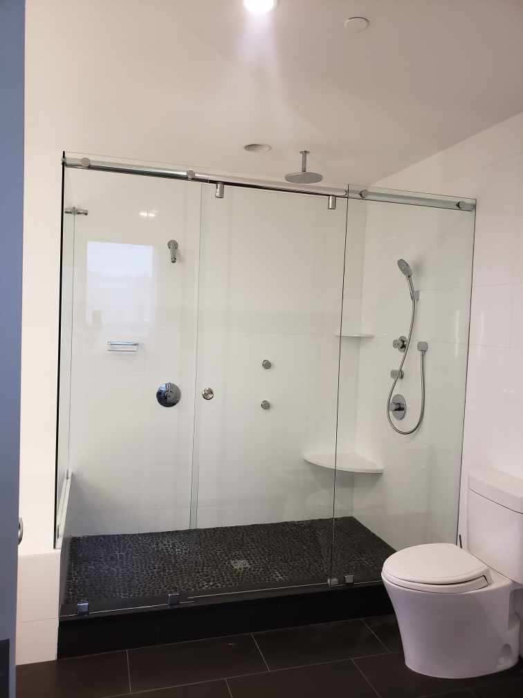 Modern bathroom with glass shower, black tiled floor, wall-mounted toilet, and white walls Modern bathroom with glass shower, black tiled floor, wall-mounted toilet, and white walls
