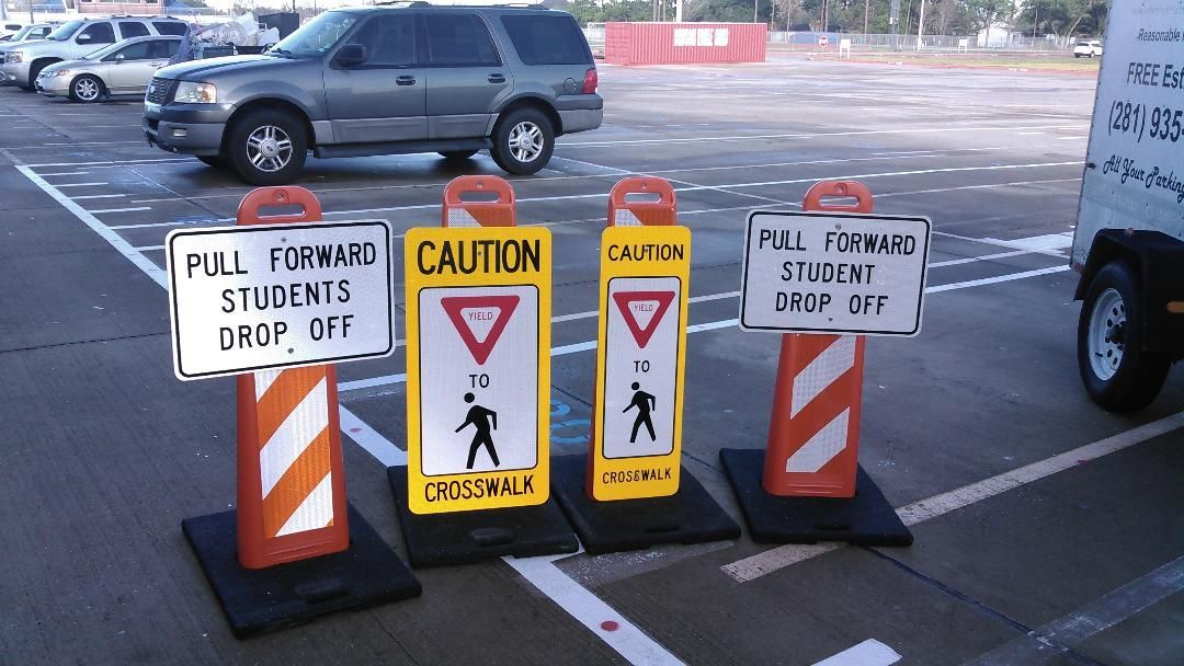 Three traffic cones in a parking lot with one that says caution