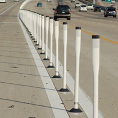 A row of white poles on the side of a highway