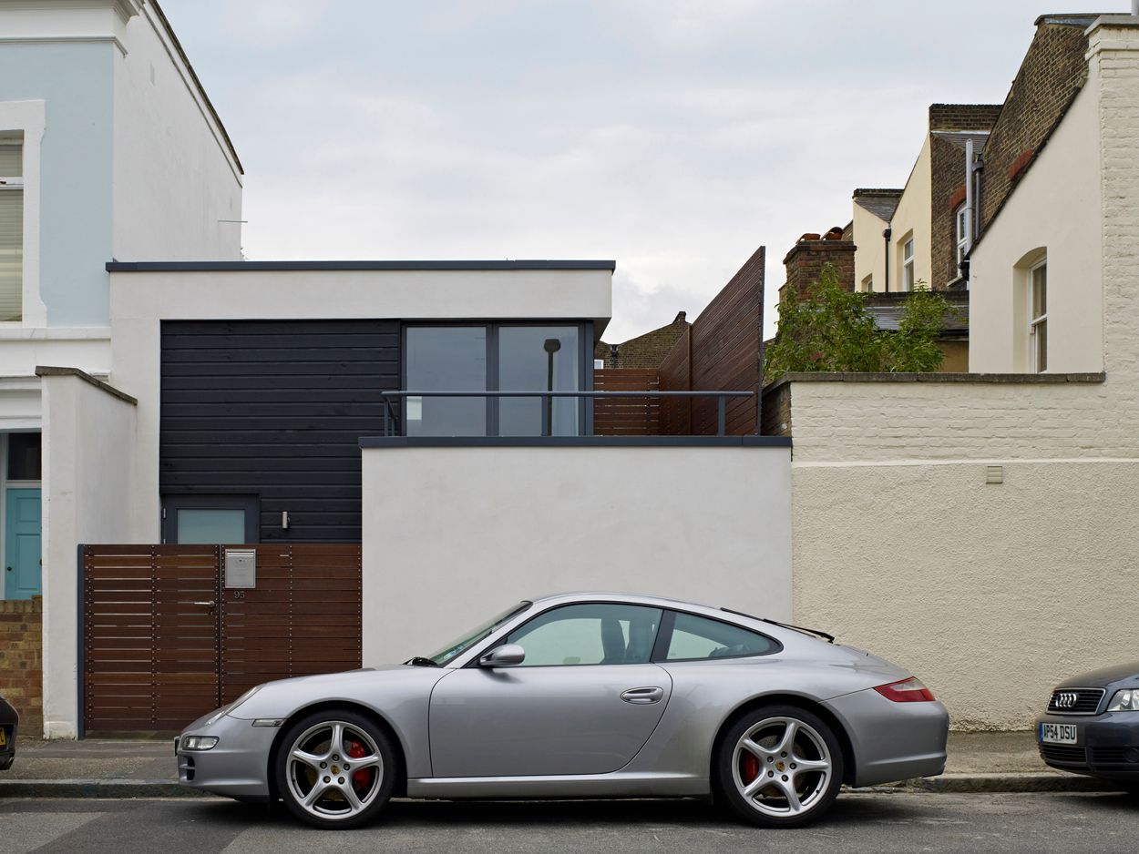 Silver sports car parked on a quiet residential street in front of modern houses.