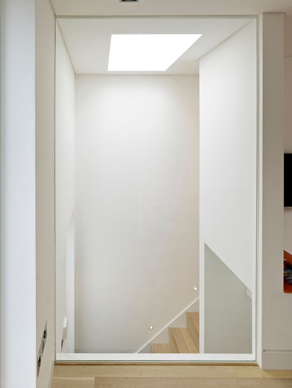 White interior stairwell with a skylight and a small section of wooden stairs visible below.