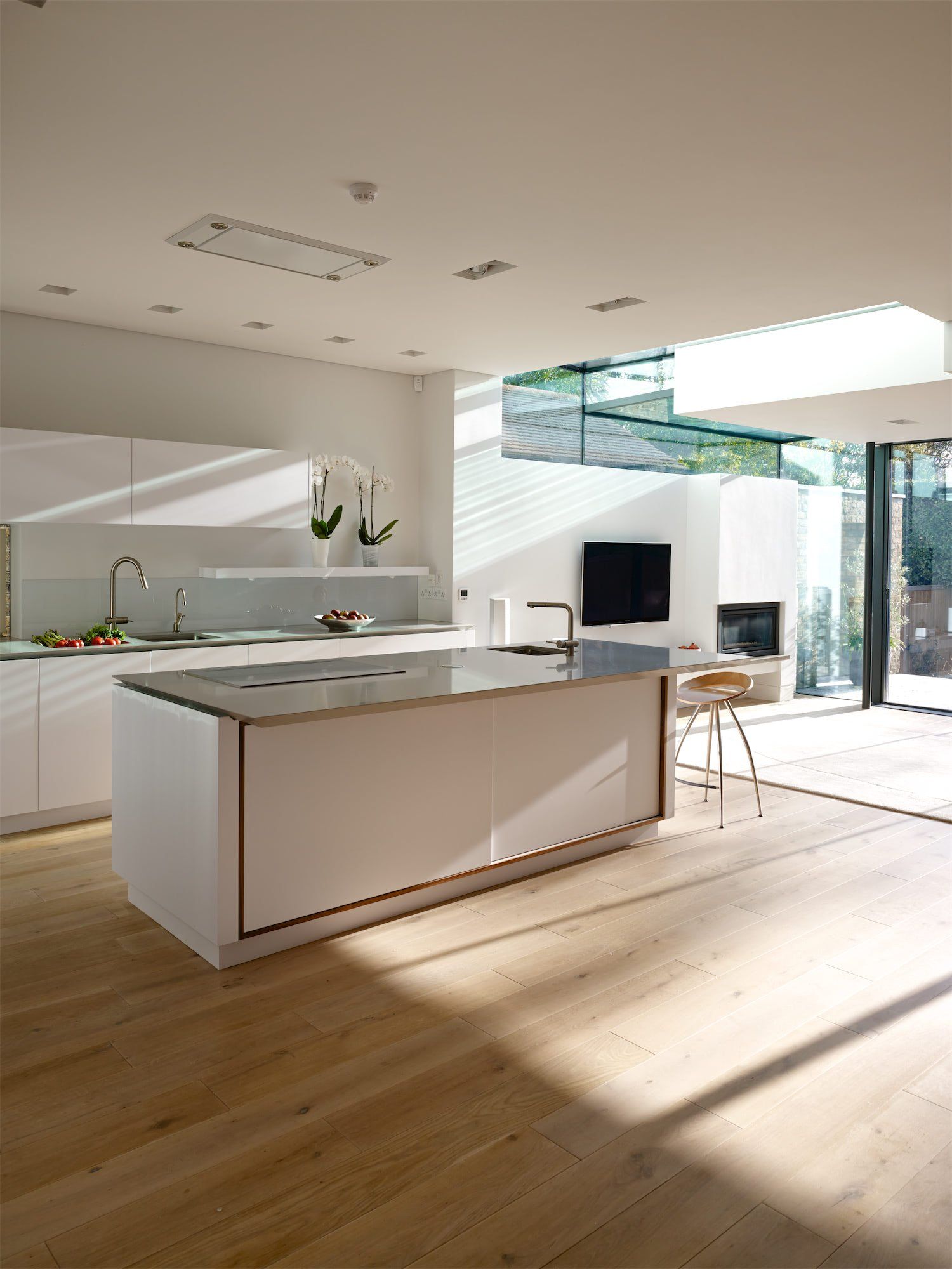 Bright modern kitchen with white cabinets, island, wood floors, and large sunlit windows
