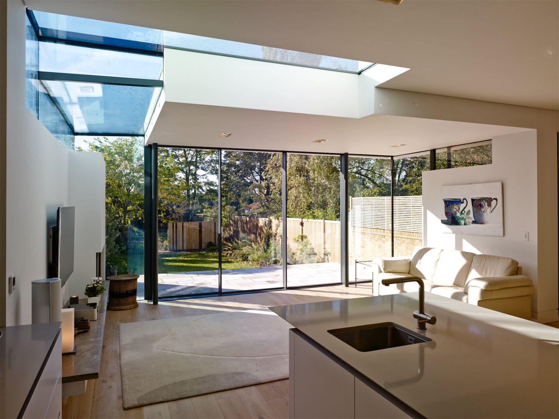 Modern living room with open glass doors, white walls, sofa, and bright natural light from the patio