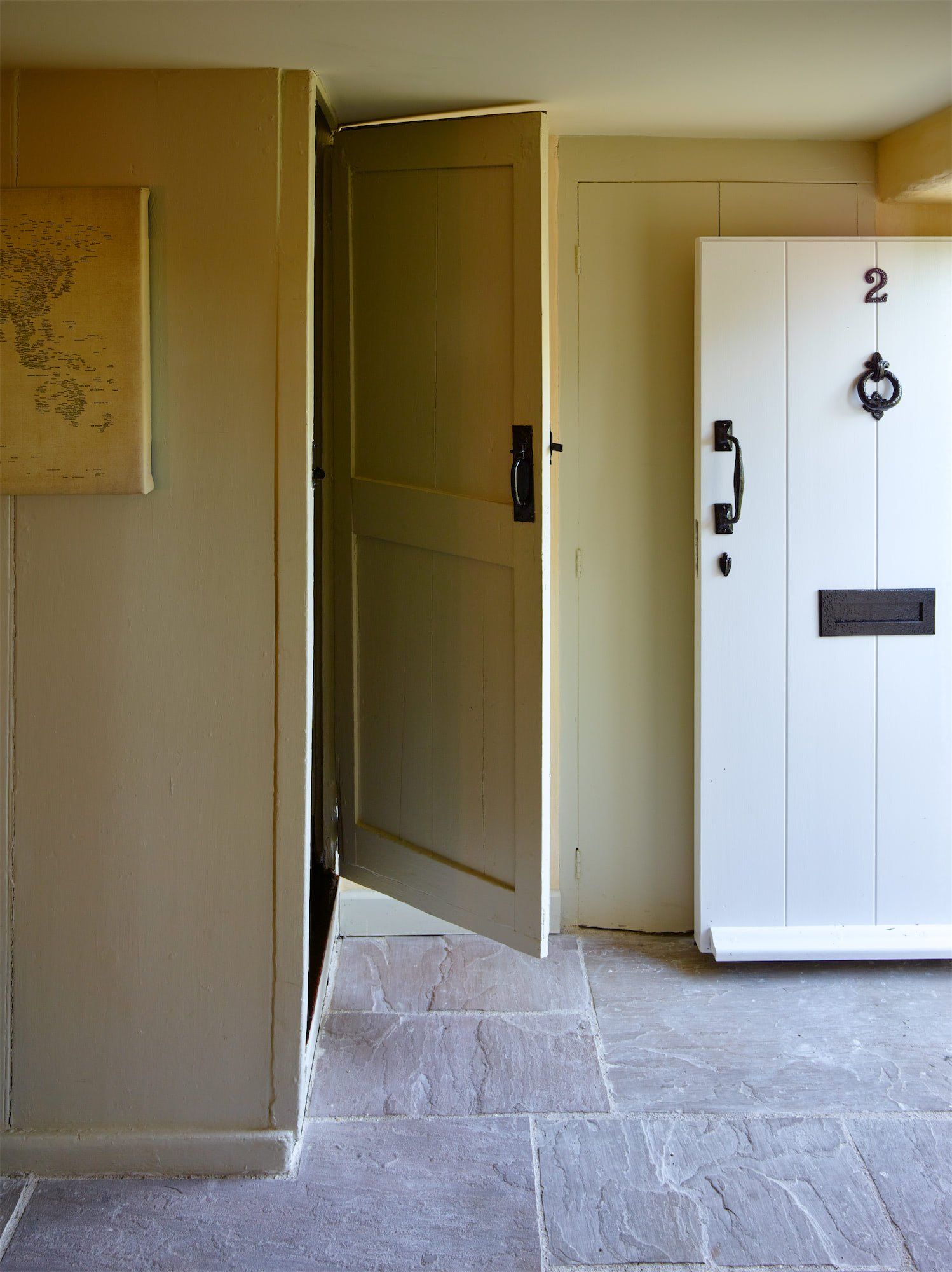 Interior hallway with beige walls and an open door beside a white cabinet marked “2”